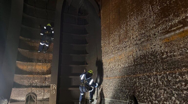 Rope access technicians inspecting internal tank structure in a confined space offshore