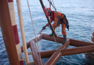IRATA rope access technician performing hydro-blasting on an offshore platform structure