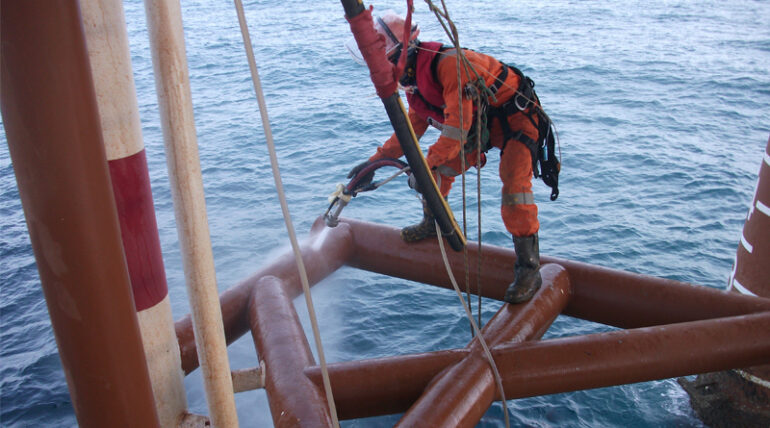 IRATA rope access technician performing hydro-blasting on an offshore platform structure